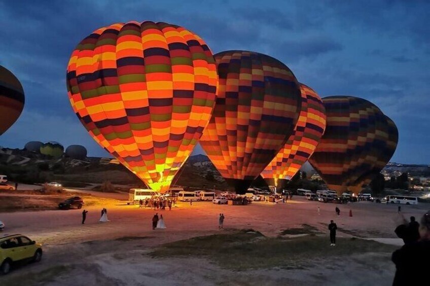 Hot air balloons at dusk with a crowd of people and vehicles on the ground. 2