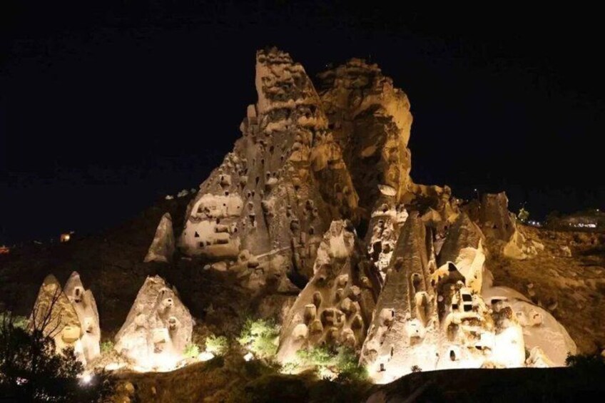 A rock formation illuminated at night with several caves and a large central peak. 3