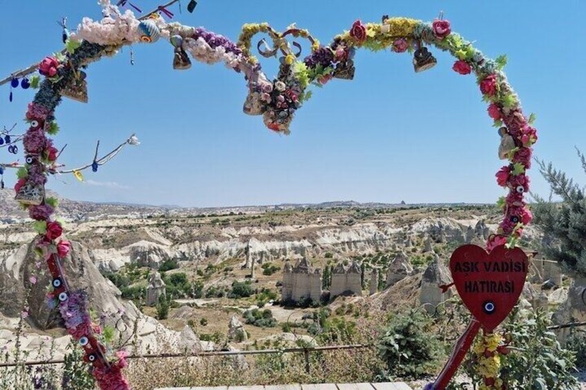 A heart-shaped arch with decorations and a sign reading 'ASK VADIŞ HATIRASI' in a rocky landscape. 4