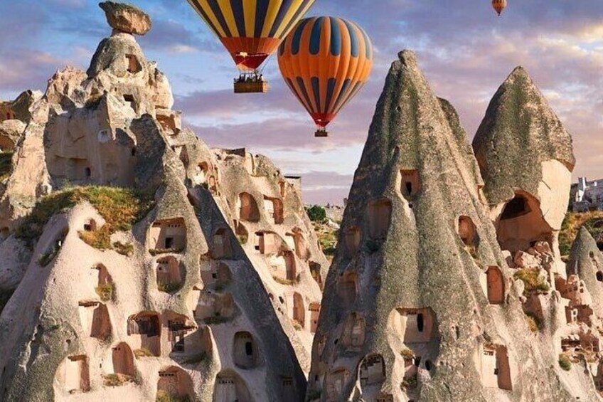 Paisaje de formaciones rocosas con numerosas viviendas excavadas en la roca y globos aerostáticos en el cielo. 5