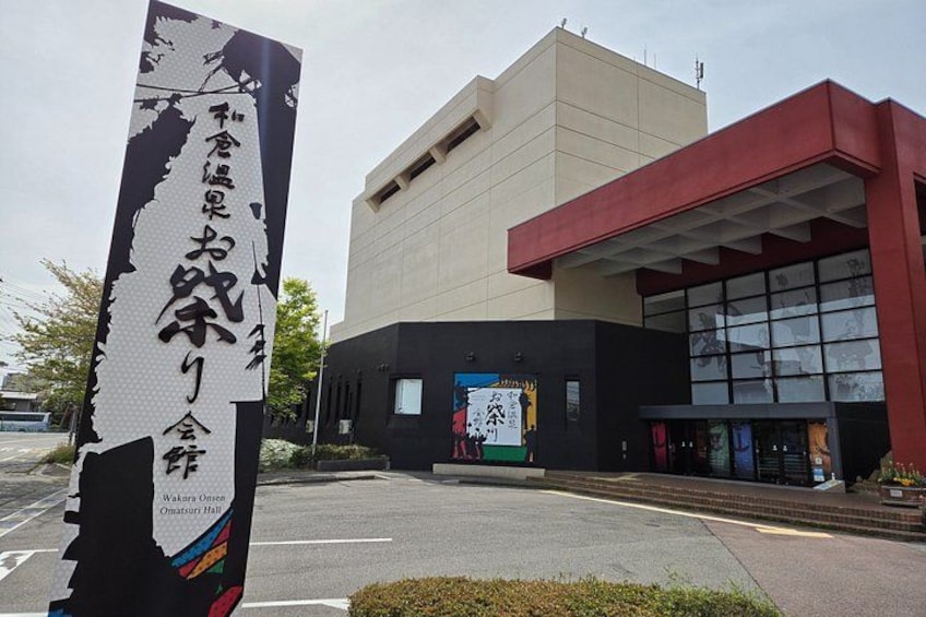 A building with a large sign in front, a parking lot, and a clear sky. 2