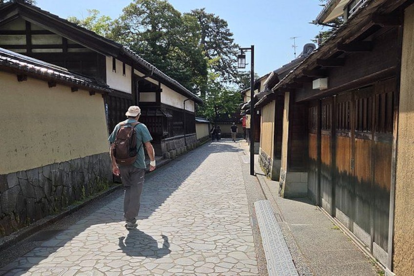 Une ruelle étroite pavée, bordée de bâtiments traditionnels aux portes et fenêtres en bois. 1