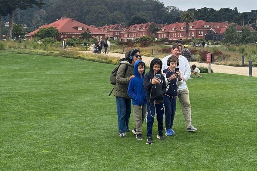 Un gruppo di persone in un prato, con edifici a tetti rossi sullo sfondo. 5
