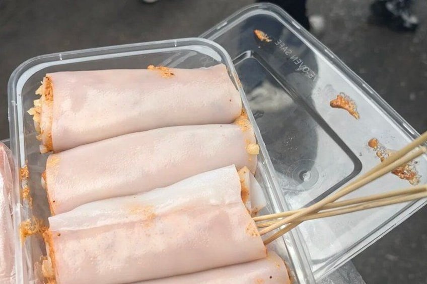 A plastic container with four spring rolls and chopsticks. 5