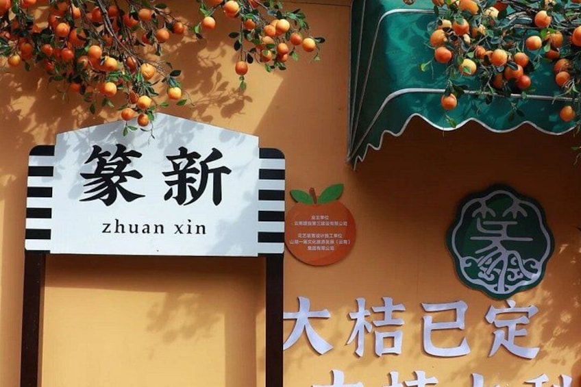 A sign with Chinese characters, a fruit display, and a logo on a wall. 1