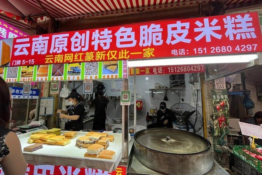 A street food stall with a large cooking pot, a display of sandwiches, and a signboard with contact information. 4