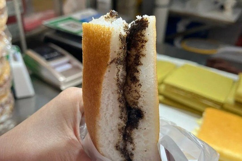 A hand holding a piece of cake with a dark filling and a light-colored crust. 2