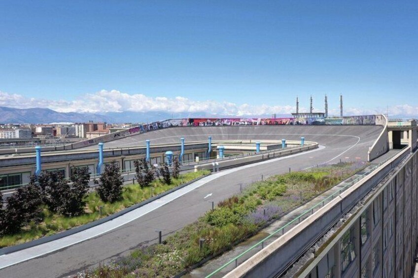 Un'autostrada con un ponte sopra, edifici industriali in lontananza e montagne sullo sfondo. 5