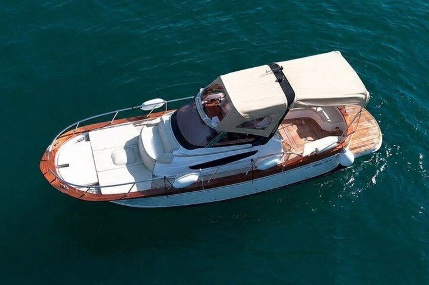 A boat with a wooden deck, white hull, and a canopy on the bow. 2