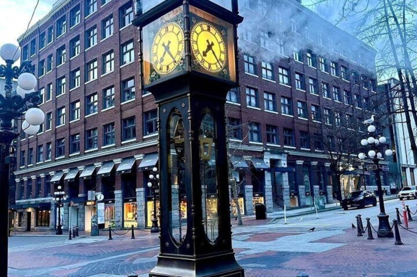 Una torre del reloj frente a un edificio de ladrillo, con una calle en primer plano. 2