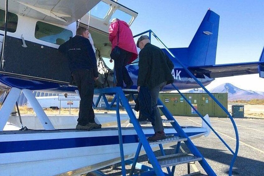 A small aircraft on a runway with people boarding it. 5