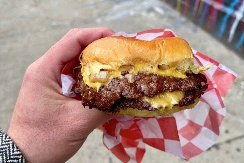 En hånd holder en burger med bolle, ost og bøf. 3