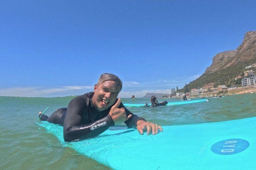 A person on a surfboard in the ocean with a clear sky and a mountainous coastline in the background. 5