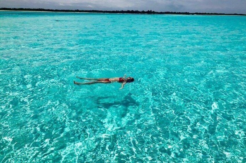 Una persona flotando en aguas turquesas cristalinas, con una costa lejana. 1