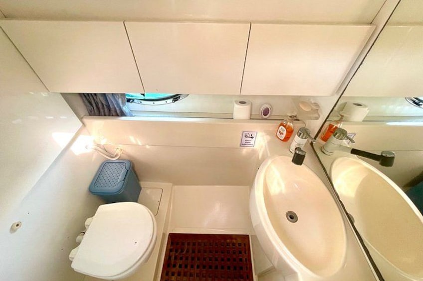 Une petite salle de bain avec des toilettes, un lavabo et un miroir. 2