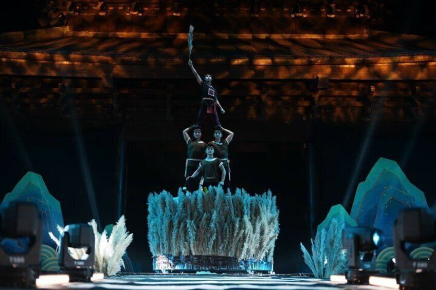 A stage with a central figure standing on a platform, surrounded by abstract structures and lighting. 1