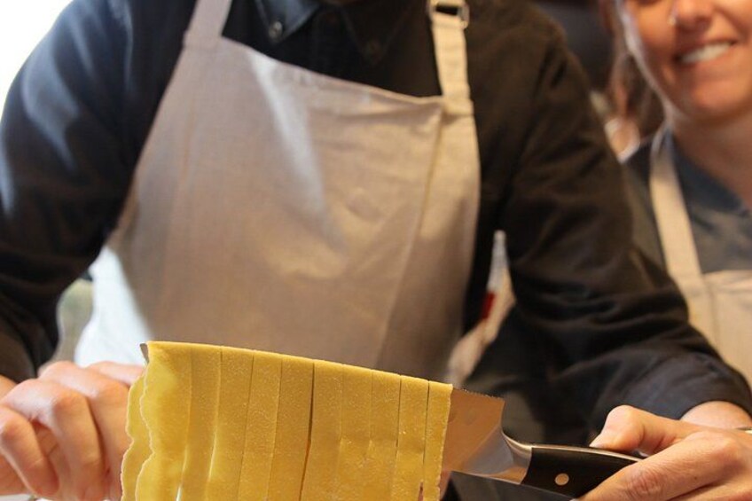 A person cutting a yellow pastry with a knife. 2