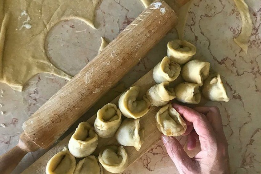 Une personne qui étale de la pâte à l’aide d’un rouleau à pâtisserie, en préparant des raviolis. 2