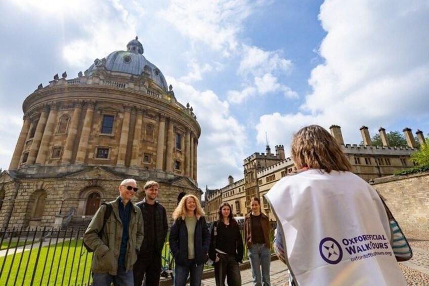 Un grupo de personas frente a un edificio histórico con una cúpula y un alto campanario. 1
