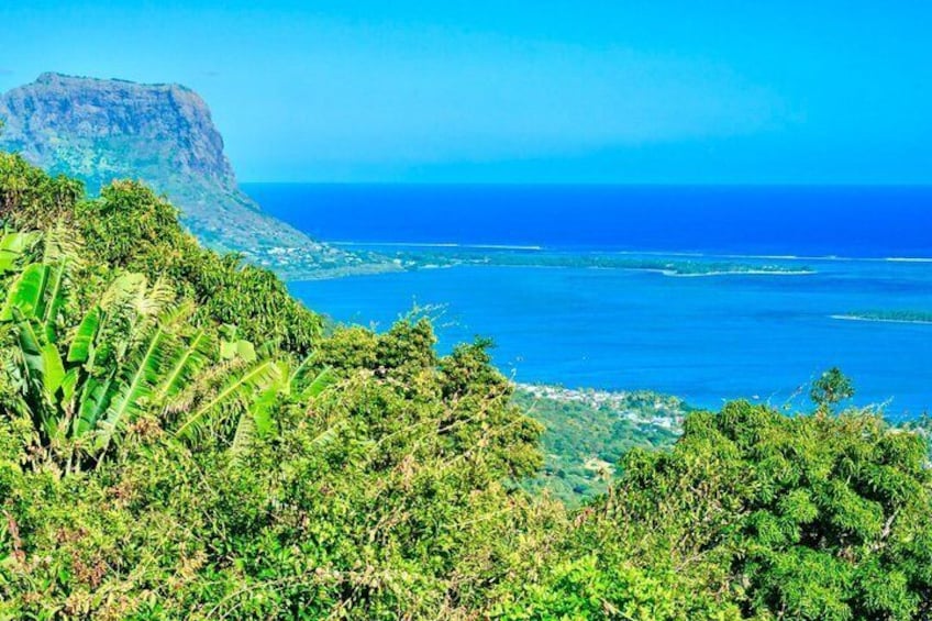 Eine Küstenlandschaft mit üppigem Grün, einem markanten Berg und einem klaren, blauen Meer. 4