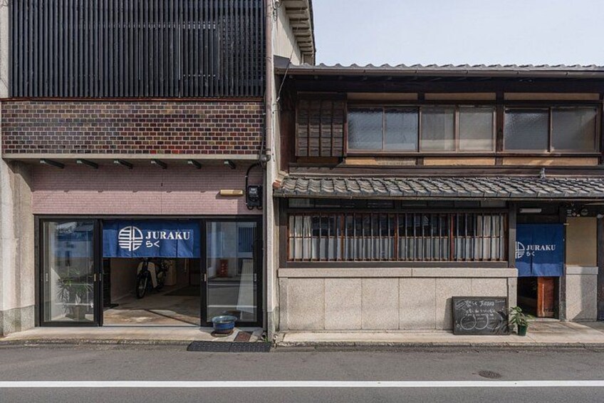 A building with a storefront labeled 'JURAKU' and a smaller adjacent building with a similar sign. 4