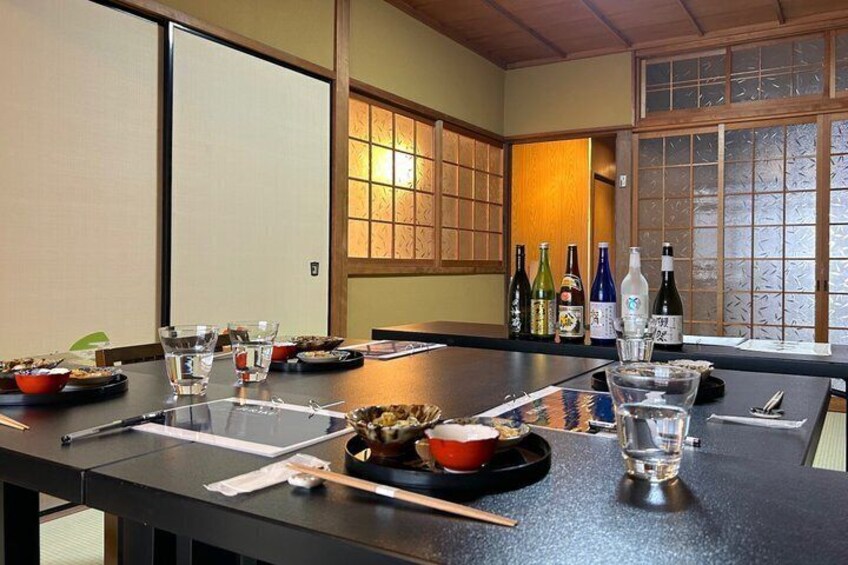 Et traditionelt japansk rum med tatamimåtter, et lavt bord med sakeflasker og en skydedør. 3