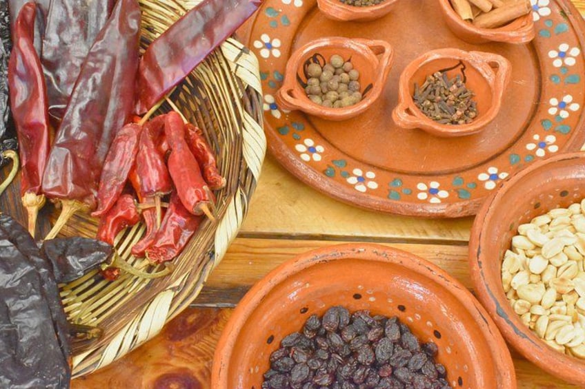 Una colección de chiles secos, especias y semillas en cuencos de terracota. 3