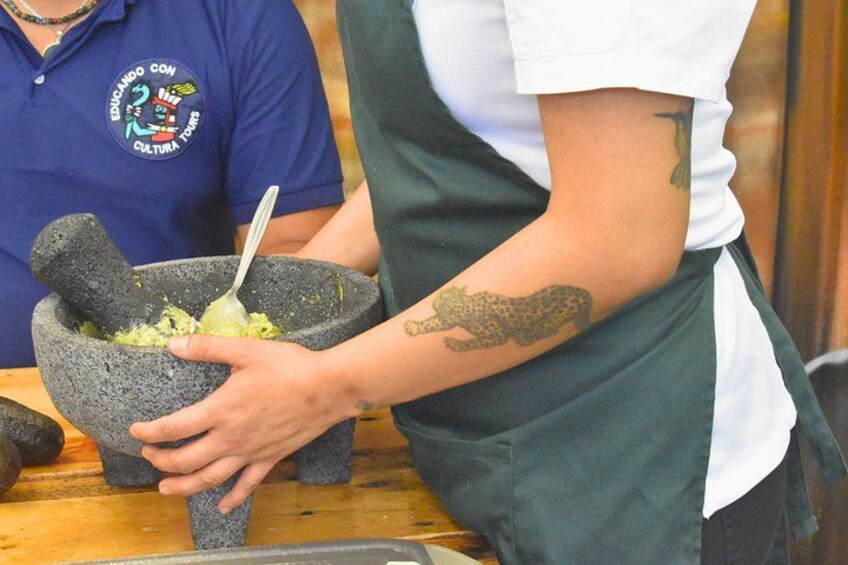 Una persona machaca alimentos en un mortero de piedra. 4
