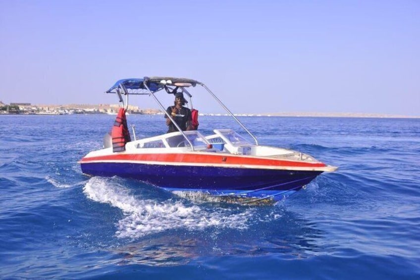 Een speedboot met een blauw-rode romp, een zonnedak en een persoon in een reddingsvest. 1