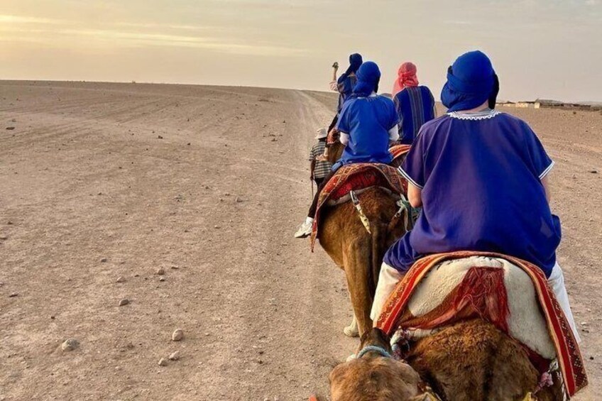 A group of people riding camels on a desert road. 4