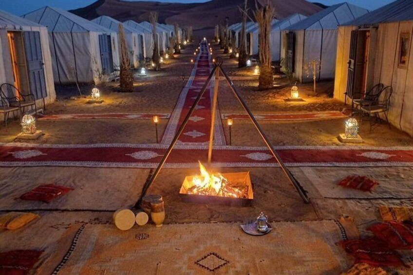 A row of tents with a central fire pit and lanterns. 2