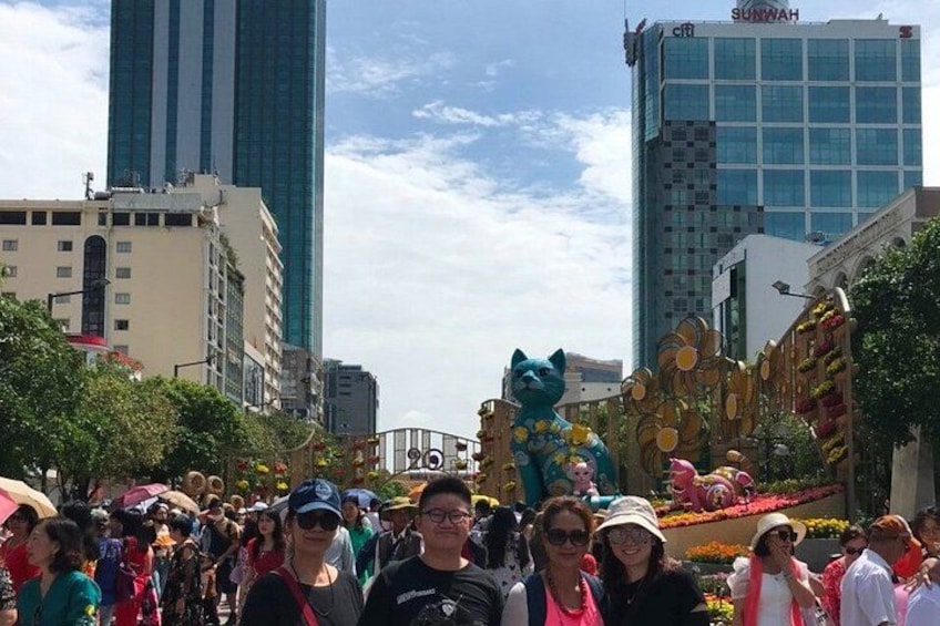 Una calle concurrida con gente, una gran escultura de elefante azul y edificios modernos. 5