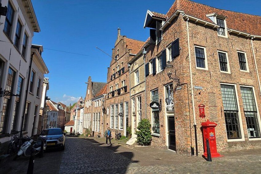 Una calle adoquinada bordeada por edificios históricos, un buzón rojo y una bicicleta. 2