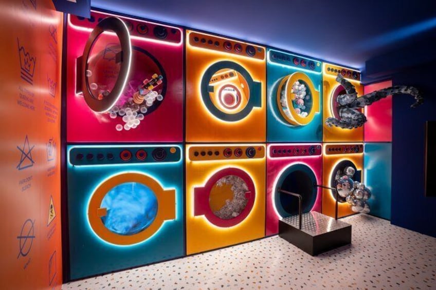 Une buanderie aux couleurs vives, équipée de plusieurs machines à laver, chacune ayant un design et un éclairage uniques. 1