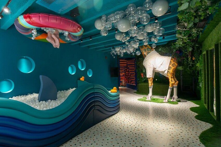 Un espace de jeux intérieur comprenant une piscine à vagues, une statue de girafe et un plafond décoré de ballons suspendus. 3
