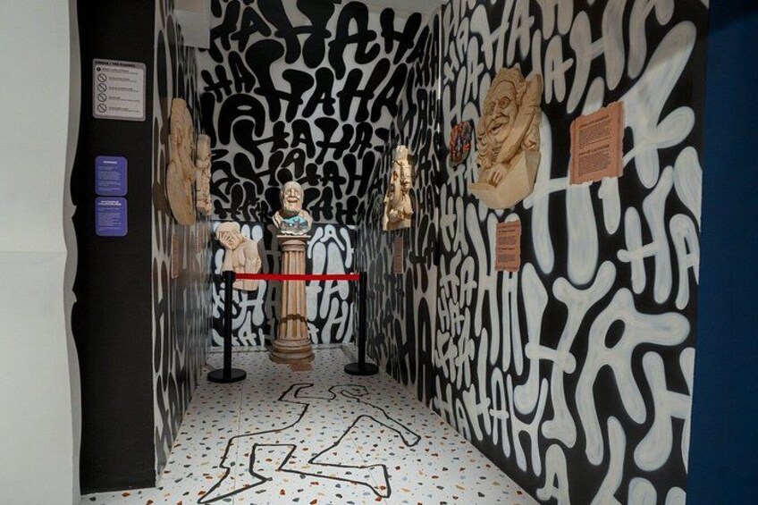 Un couloir orné d’œuvres d’art murales abstraites, avec une sculpture en buste au centre et des panneaux d’information. 4