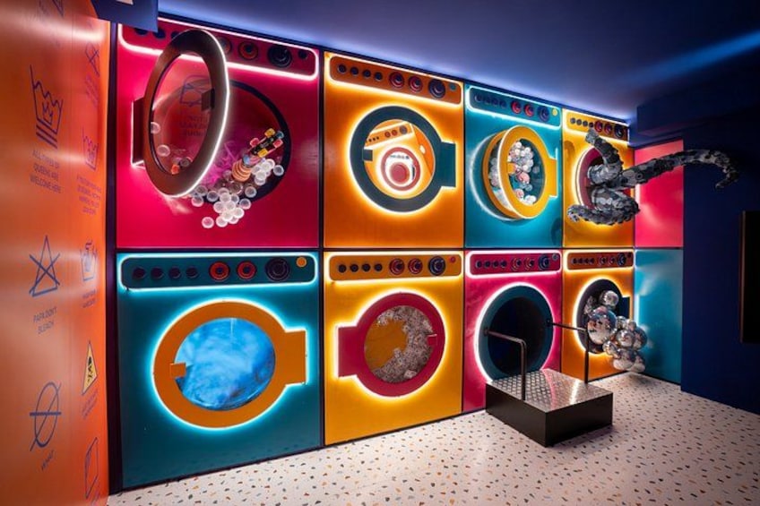 Une buanderie aux couleurs vives, équipée de plusieurs machines à laver et d’un bras robotisé. 1