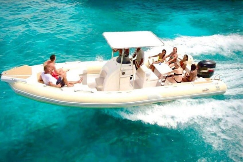 Una piccola barca gonfiabile con persone a bordo che scivola in acque cristalline. 1