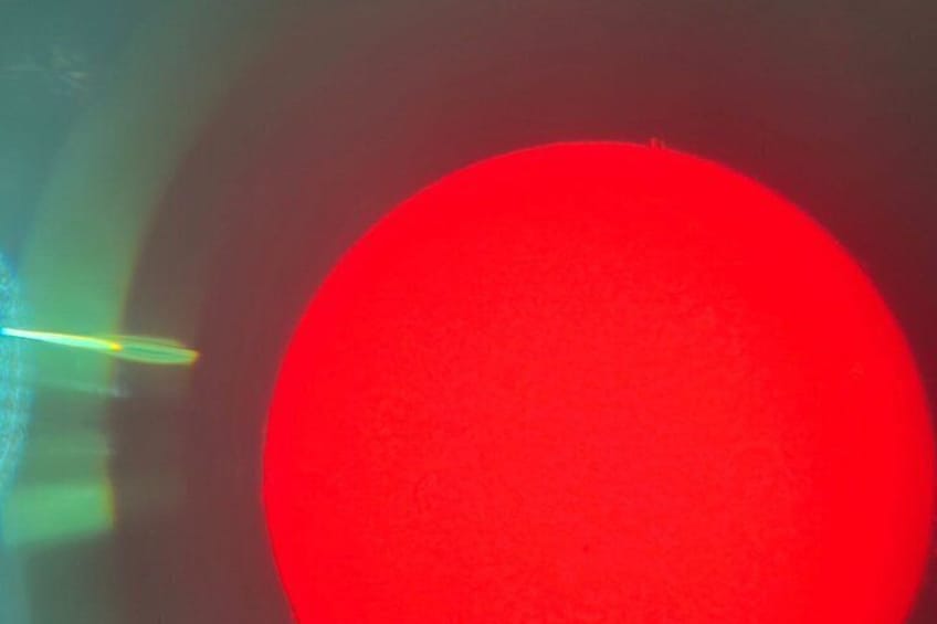 Un objet circulaire rouge avec une lumière verte floue en arrière-plan. 3
