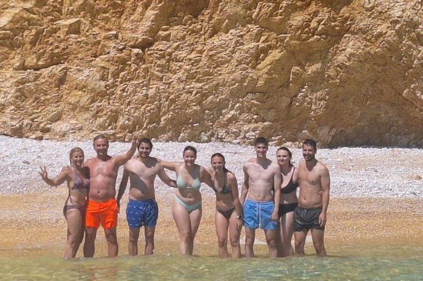 A group of people standing in shallow water with a rocky cliff in the background. 3