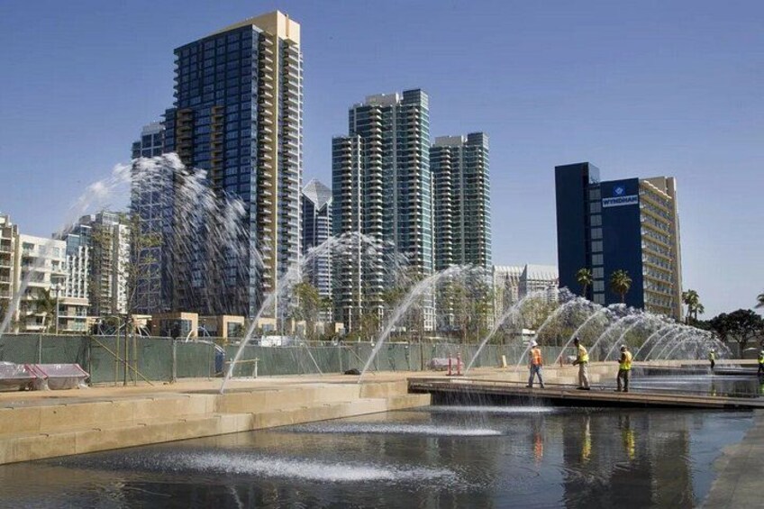 Une fontaine avec des jets d’eau, située sur une place et entourée d’immeubles imposants. 2