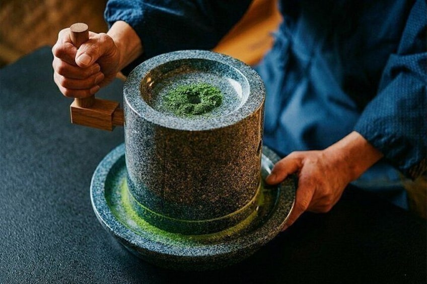 Una persona moliendo polvo verde con un mortero de piedra y un mortero de madera. 3