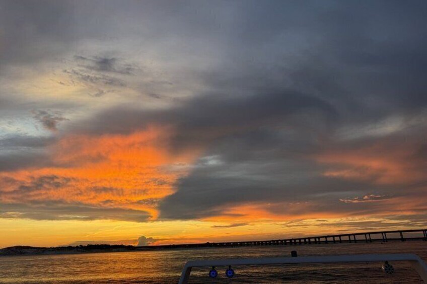 A sunset over a body of water with a bridge in the distance. 4