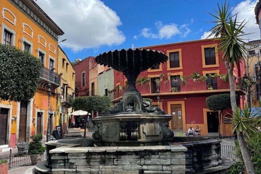 A fountain in a plaza surrounded by colorful buildings. 5