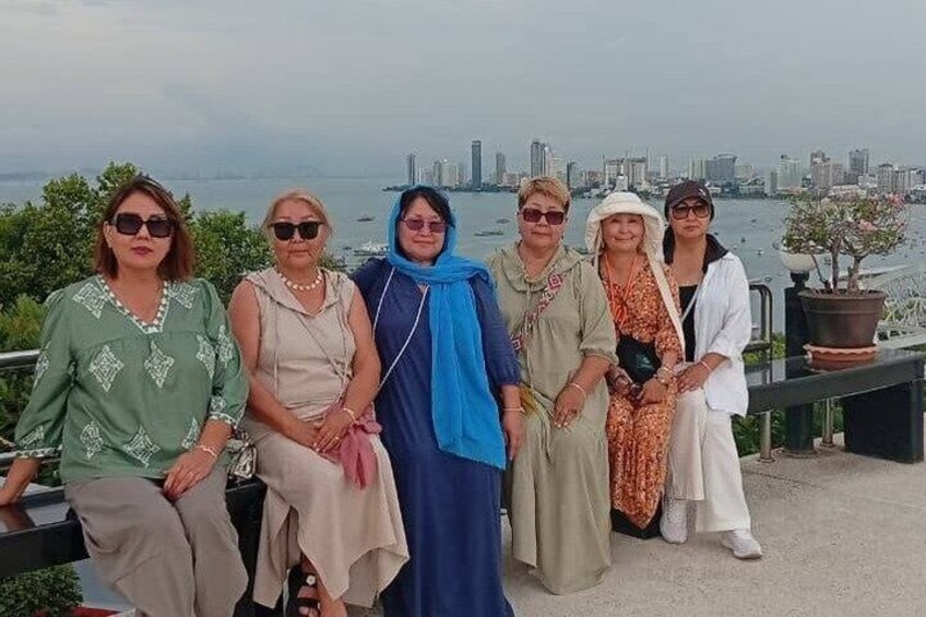 Un grupo de personas sentadas en un banco con un horizonte urbano y agua de fondo. 4