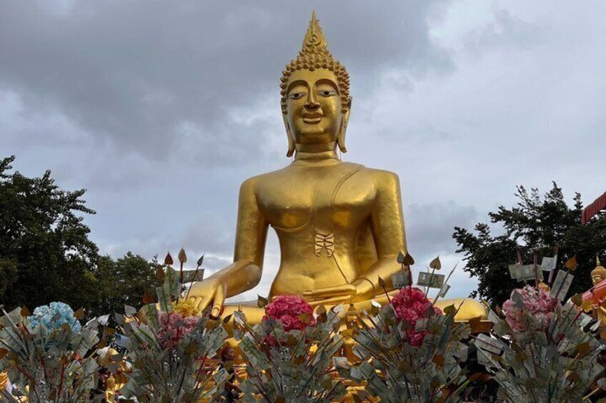 Una gran estatua dorada de Buda rodeada de flores coloridas. 2