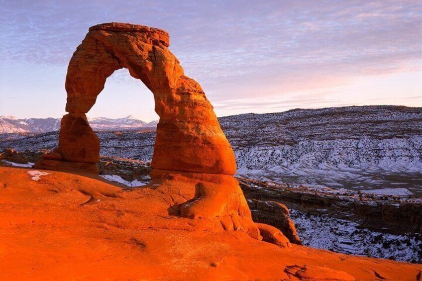 A natural rock arch formation with a snow-covered landscape in the background. 2
