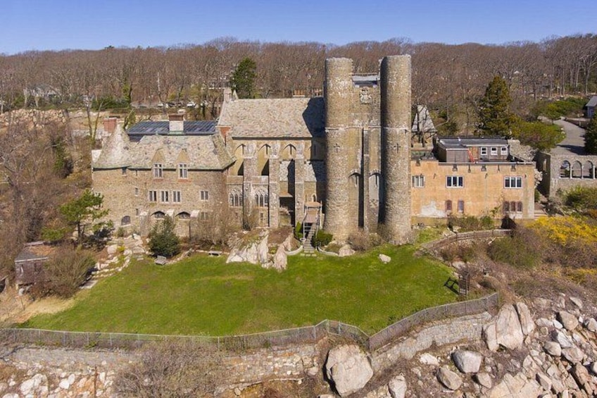 Un castillo de piedra histórico con torres, un césped verde y un muro de piedra. 1