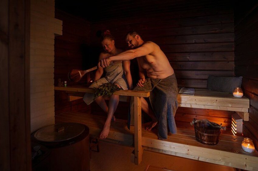 Una sauna con bancos de madera, un balde y velas. 1