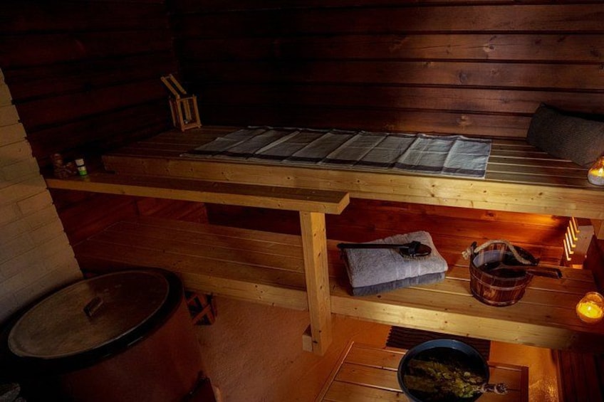 Una sauna de madera con bancos, una toalla, un cubo y una vela. 3
